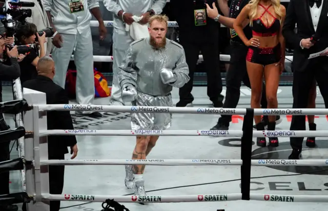 Jake Paul in a silver outfit and shorts in the ring