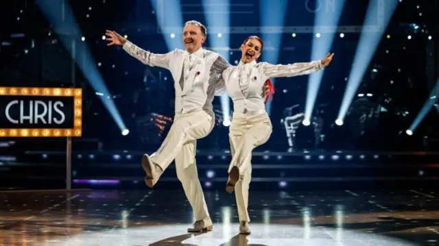 Chris McCausland and Diane Buswell dancing in white outfits on Strictly Come Dancing