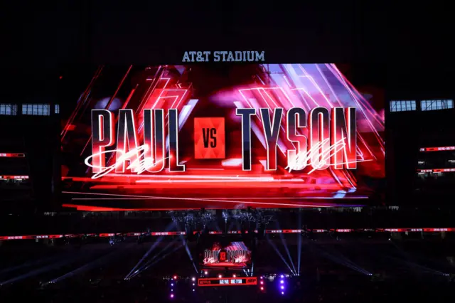 A large screen above a boxing ring displaying Paul vs Tyson