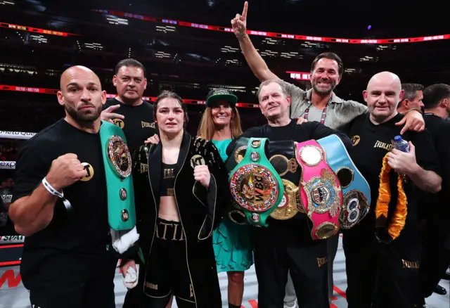 Katie Taylor holds her light-welterweight titles and poses with her trainers