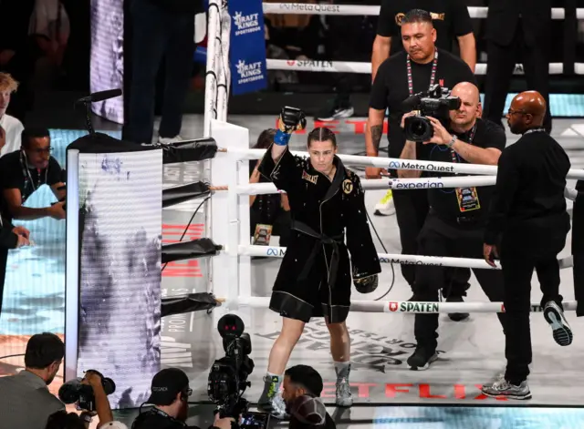 Katie Taylor raises her arm before she enters the ring