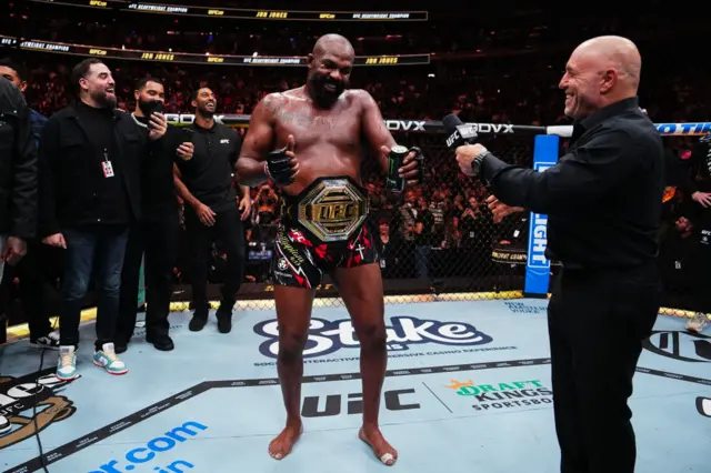 Jon Jones wearing his UFC heavyweight title next to Joe Rogan