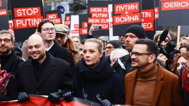 Critics of the Kremlin at a anti-war protest in Berlin 17 Nov 2024. Vladimir Kara-Murza, left, Yulia Navalnaya, centre, and Ilya Yashin, right, hold a banner with a large crowd behind them, holding 