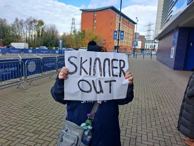 A fan holds a Skinner Out sign