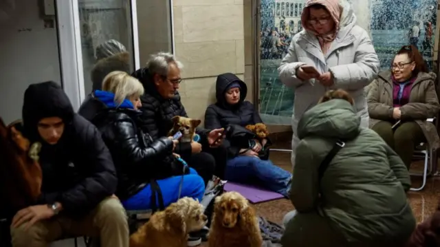 Group of people seeking shelter in Kyiv metro station with several pet dogs pictured