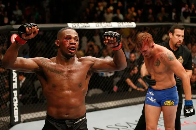 Jon Jones holds up his arms with Alexander Gustafsson in the background