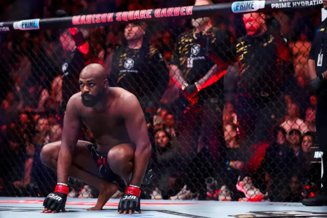 Jon Jones crouches down in the octagon