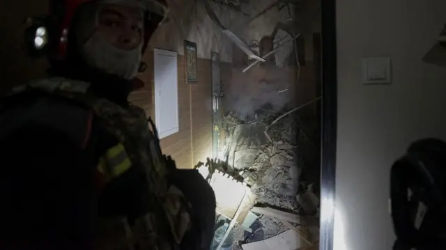 An rescue worker stands inside a building that appears to have been damaged by a Russia strike