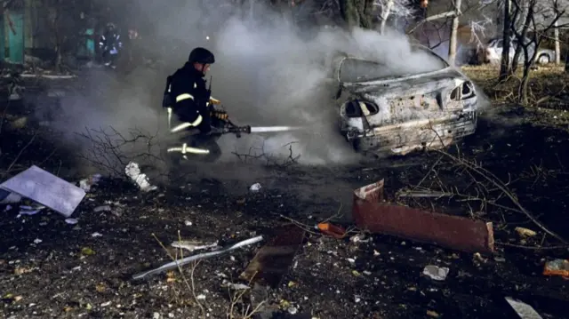 Firefighter putting out fire on car