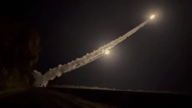 At night, a missile flies into the air, leaving a trail of smoke behind it