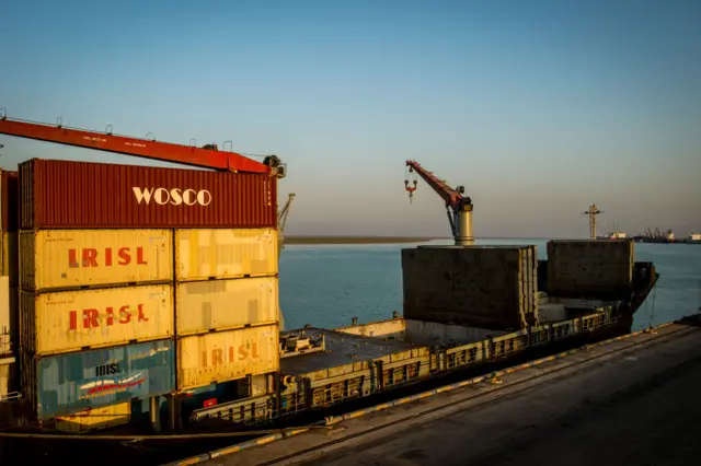 A cargo ship at a port with several shipping containers waiting to be unloaded