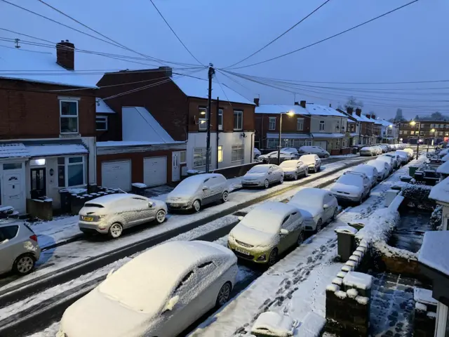 Cars covered in snow parked on a street