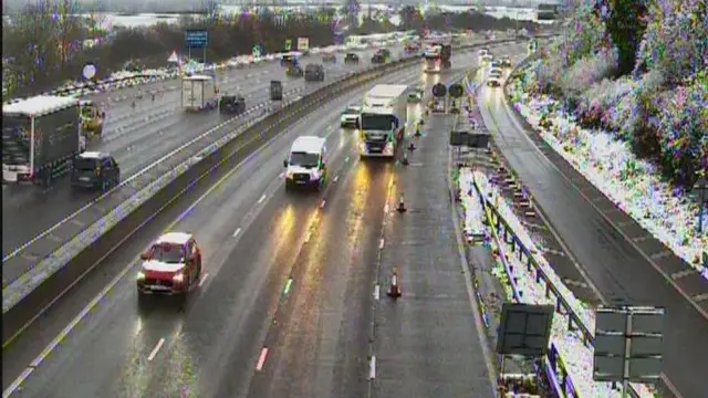 Cars and lorries on a motorway, seen in both directions with snow on the side of the route