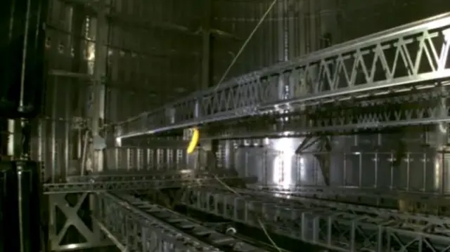 A banana dangling amid the inside of a rocket, surrounded by metal framework