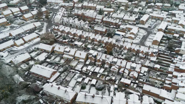 Snow covers rooftops in a town with homes across a wide area covered