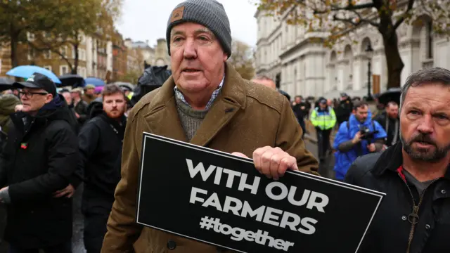 Jeremy Clarkson holds a sign saying "with our farrmers #together" at the London protest