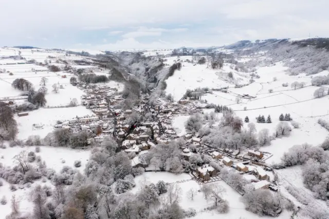 A drone image of Stoney Middleton with snow covering houses and snow-covered fields surrounding the area