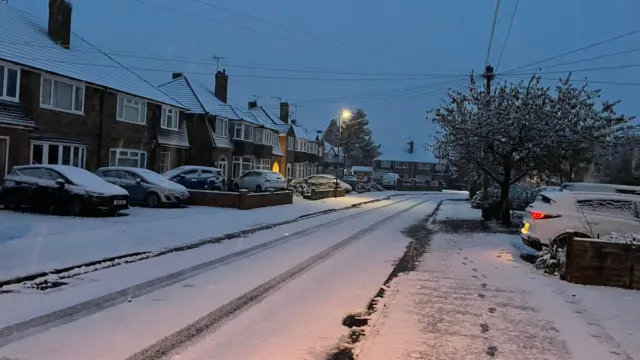 Snow across a residential road in Tiddington, near Stratford-upon-Avon, with snow covering the roofs of houses and cars