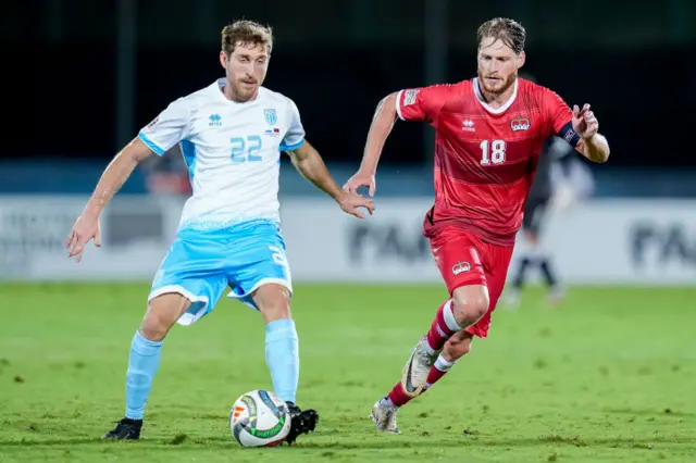 Nicolas Hasler of Liechtenstein and Marcello Mularoni of San Marino compete for the ball