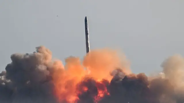 Fire and smoke billows underneath the SpaceX rocket