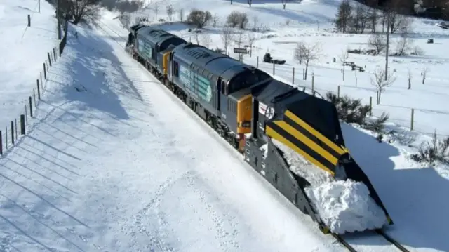 Train on rail track covered in snow along with fields also covered in snow