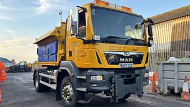 A yellow gritting lorry on a road