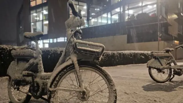 Bikes standing in light snow in a dark street