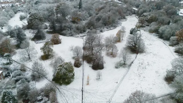 People walk through a snow-covered Priory Park after overnight snowfall in Warwick