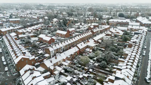 An aerial shots of dozens of houses in Warwick covered in snow stretching off to the distance