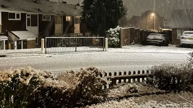 Snow across a residential road in Stourbridge with snow covering cars, railings and a fence