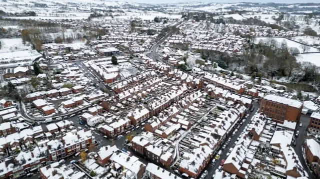 A drone view shows snow covering the roof tops of terrace housing in Leek, Stafordshire