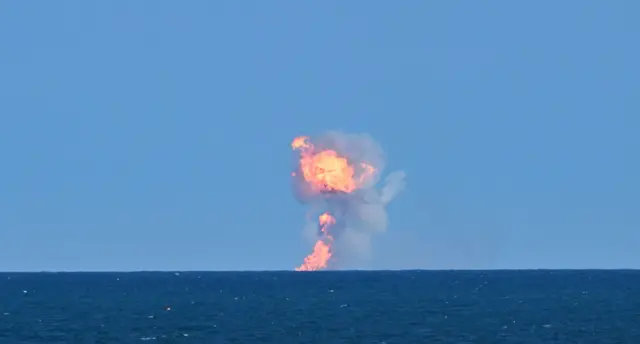 A cloud of smoke and fire as a rocket lands in sea