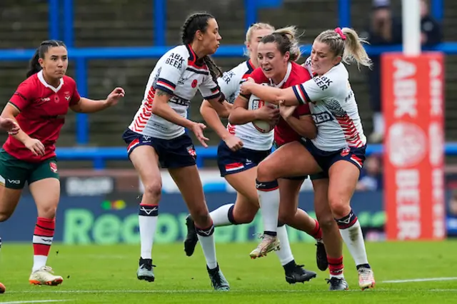 Georgia Taylor of Wales is tackled by Eboni Partington of England and Zoe Harris of England