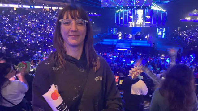 Emily stands facing the camera with the main stage behind her.