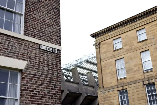 A view of one of the St James' Park stands in-between two buildings on St James Street