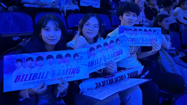 Three fans displaying signs that read "Bilibili Gaming"