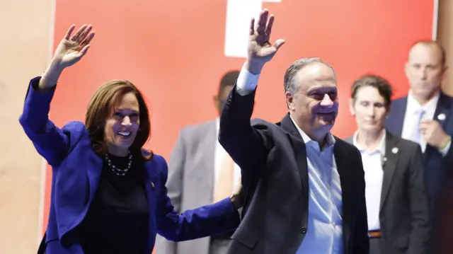 President Kamala Harris (L) and second gentleman Doug Emhoff (R) wave to supporters as they leave the stage after a campaign rally