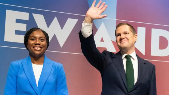 Kemi Badenoch and Robert Jenrick on stage at Tory conference, Jenrick is waving and Badenoch is smiling