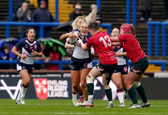 Amy Hardcastle (left) holds of tackled from Wales' Shaunni Davies (centre) and Wales' Sara Jones