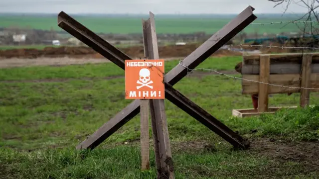 A sign warning of a minefield stands near a defence position