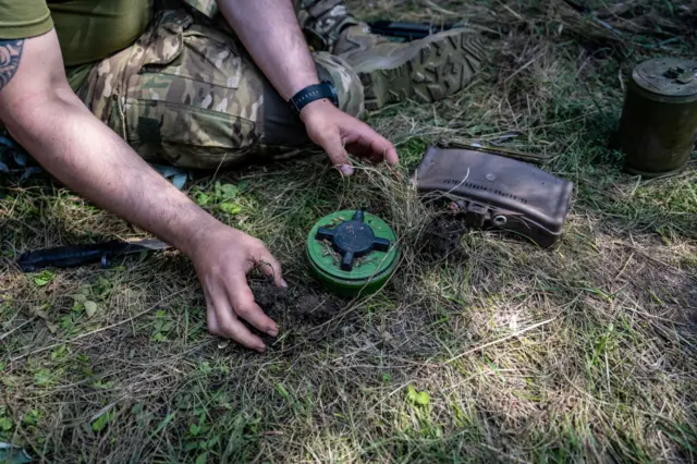 A Ukrainian de-mining sapper who gave the name Pavlo demonstrates how Russian forces place an anti-personnel mine on top of a fragmentation grenade