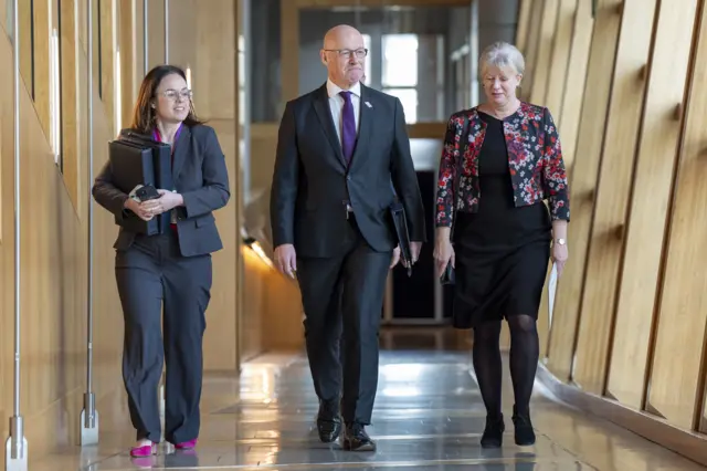 Deputy First Minister Kate Forbes, First Minister John Swinney and Finance Secretary Shona Robison walking up the corridor to the chamber