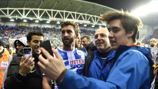 Will Grigg celebrates with Wigan fans after beating Manchester City in 2018
