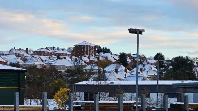 A view of a town with snow covering the rooves of dozens of houses