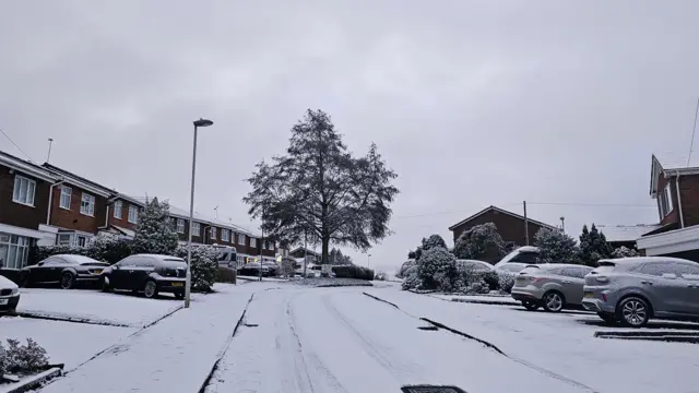 Housing estate with cars and road covered in snow