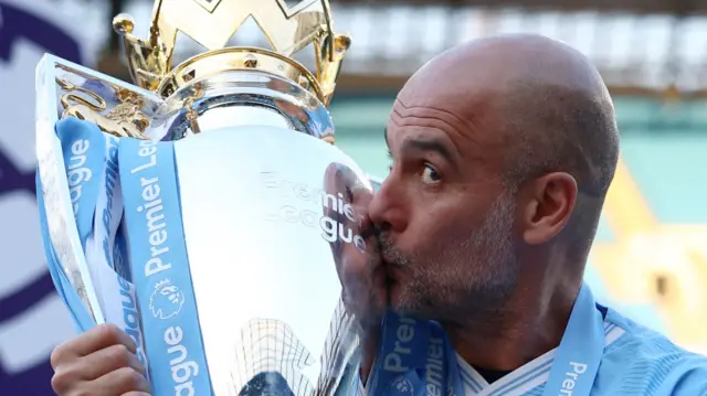 Manager Pep Guardiola kisses the Premier League trophy after Manchester City win the title in 2024