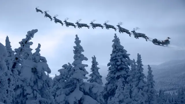 Snow covered trees with a flying sleigh and reindeer in the distance