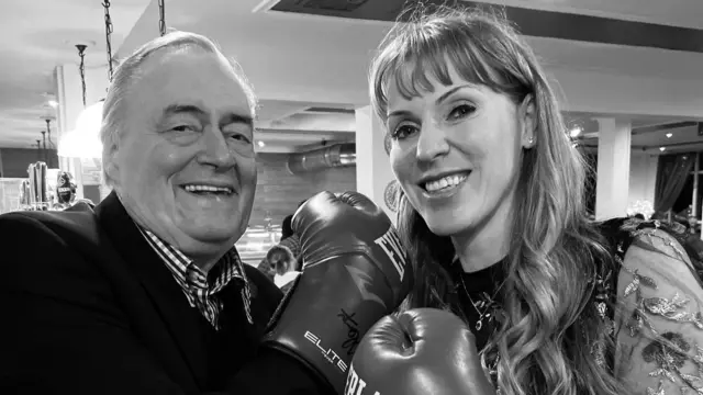 Black and white image of John Prescott and Angela Rayner play-fighting. They're both wearing boxing gloves