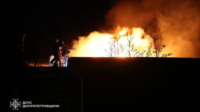 A fireball is shown over a building in shadow at the scene of a missile strike in Ukraine