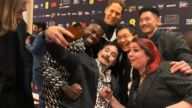 Attendees capture a selfie before the Golden Joystick Awards backdrop